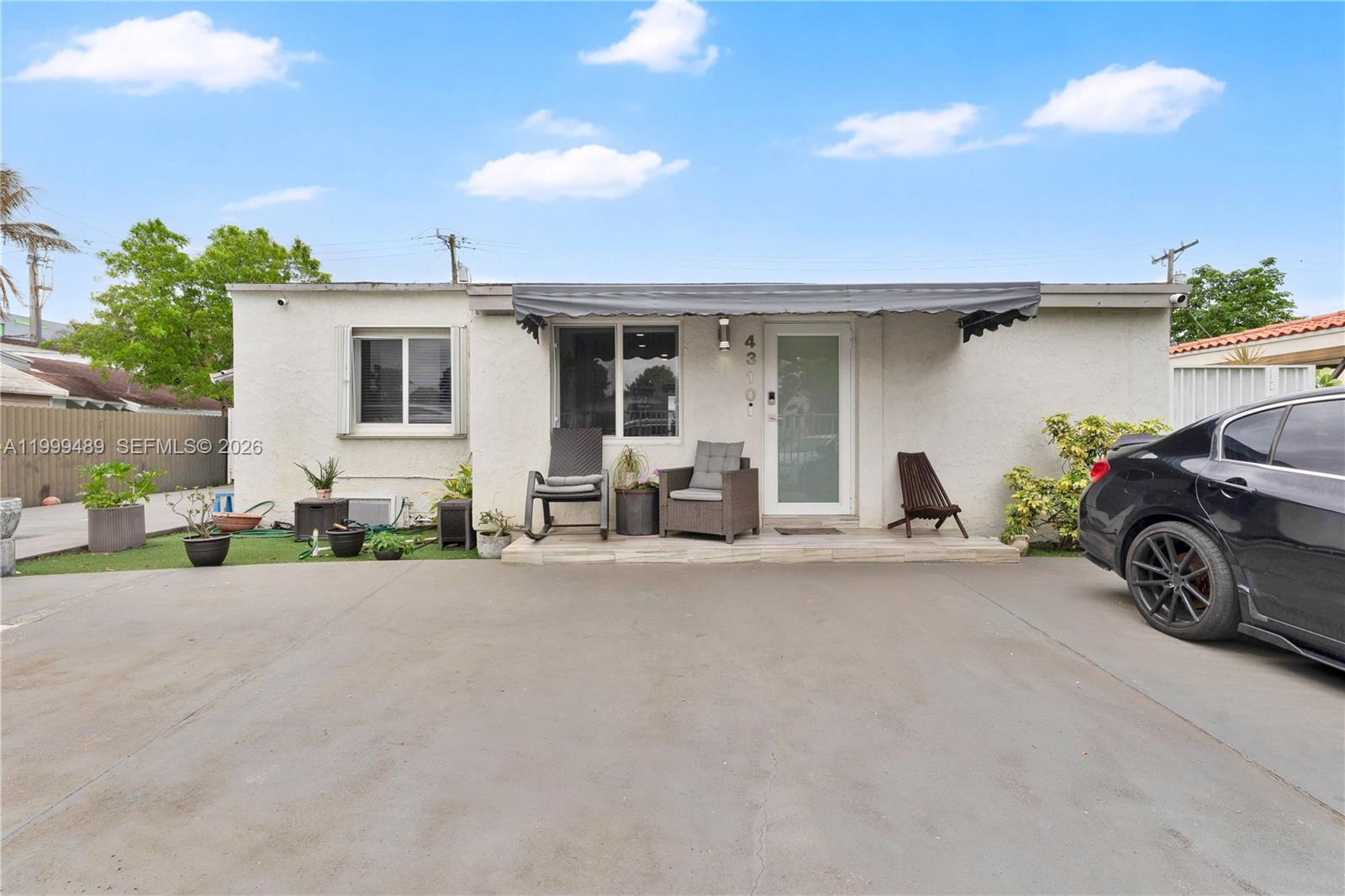 The exterior of a single-story house features a concrete driveway, a small patio, and an awning — 4310 SW 7th St, Miami FL 33134, MIAMI, FL