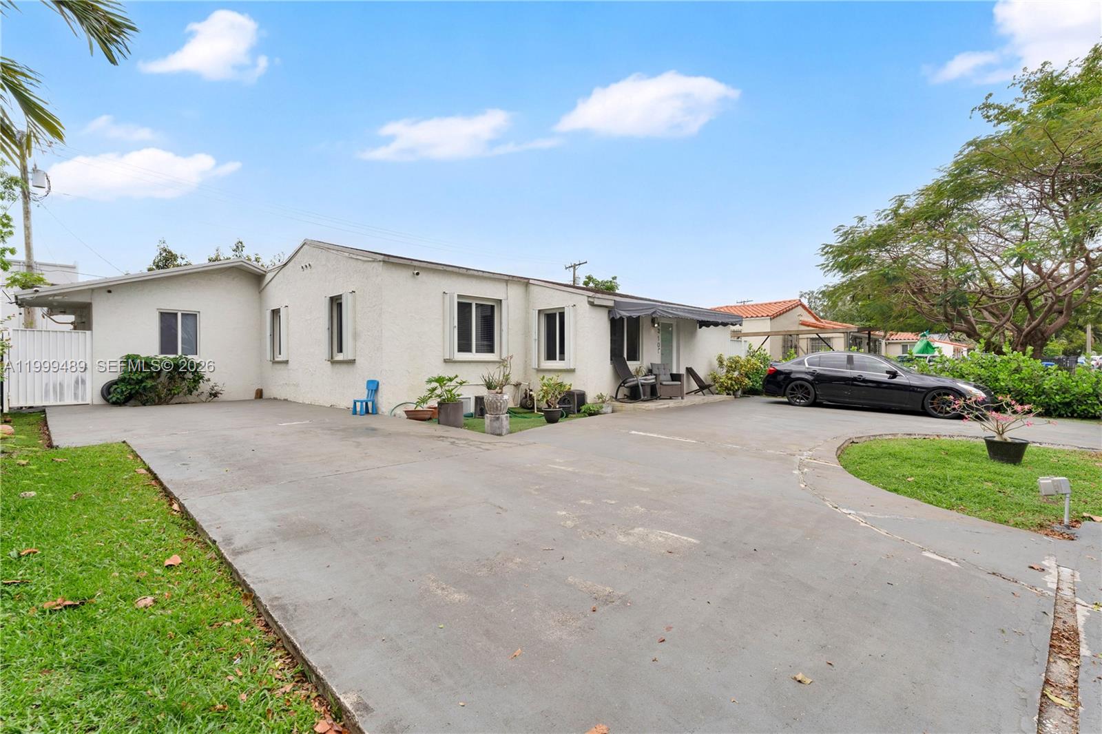 A single-story white house with a large concrete driveway and a black sedan parked outside — 4310 SW 7th St, Miami FL 33134, MIAMI, FL