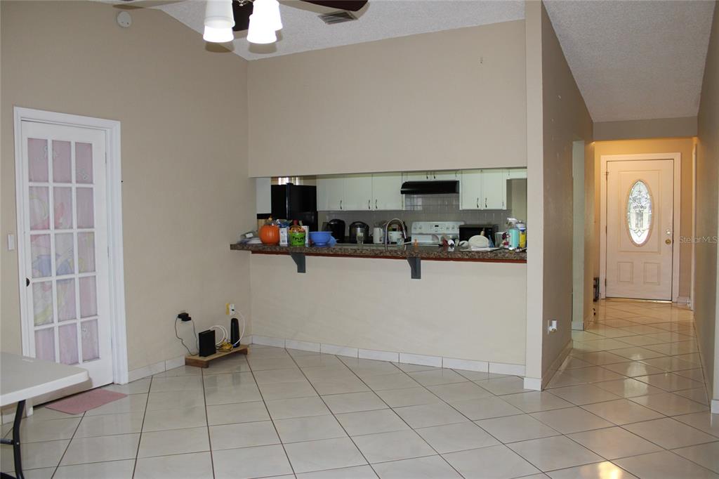 A kitchen with a breakfast bar overlooks a tiled dining area near the front entrance — 6121 56TH AVENUE N, ST PETERSBURG, FL