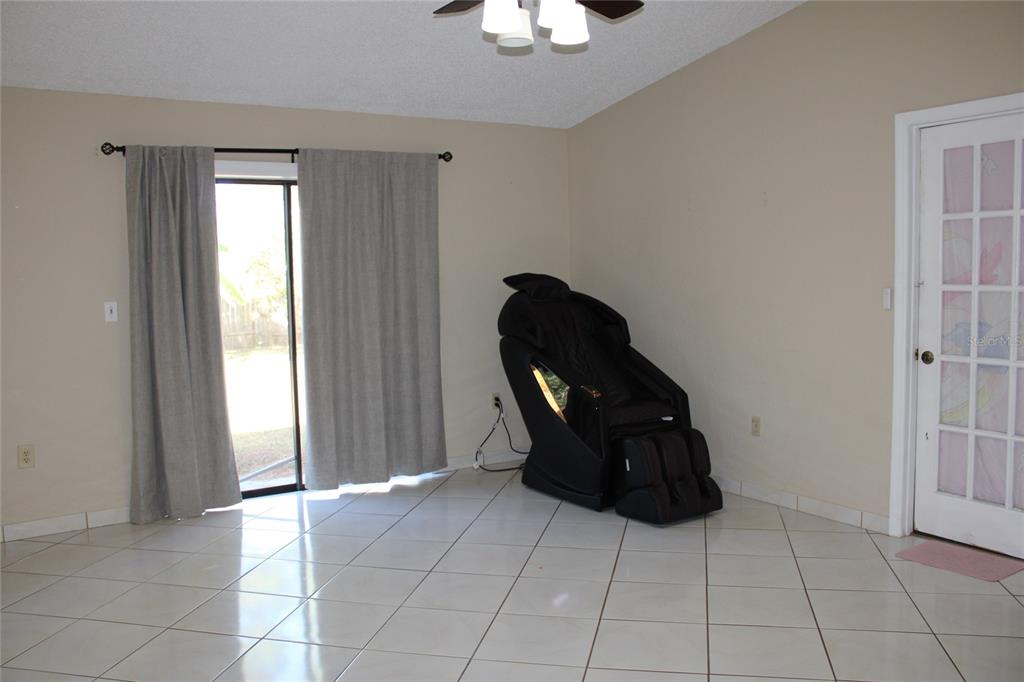 A room with white tiled floors, a sliding glass door, and a black massage chair — 6121 56TH AVENUE N, ST PETERSBURG, FL