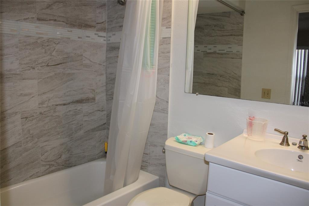 A bathroom features a white vanity, a toilet, and a bathtub with tiled walls — 6121 56TH AVENUE N, ST PETERSBURG, FL