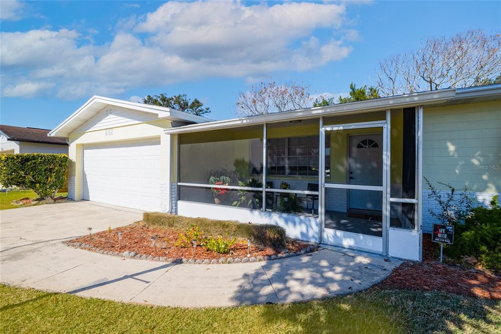 A single-story house with a two-car garage, a screened-in front porch, and a landscaped yard — 692 GASLIGHT DRIVE, SOUTH DAYTONA, FL