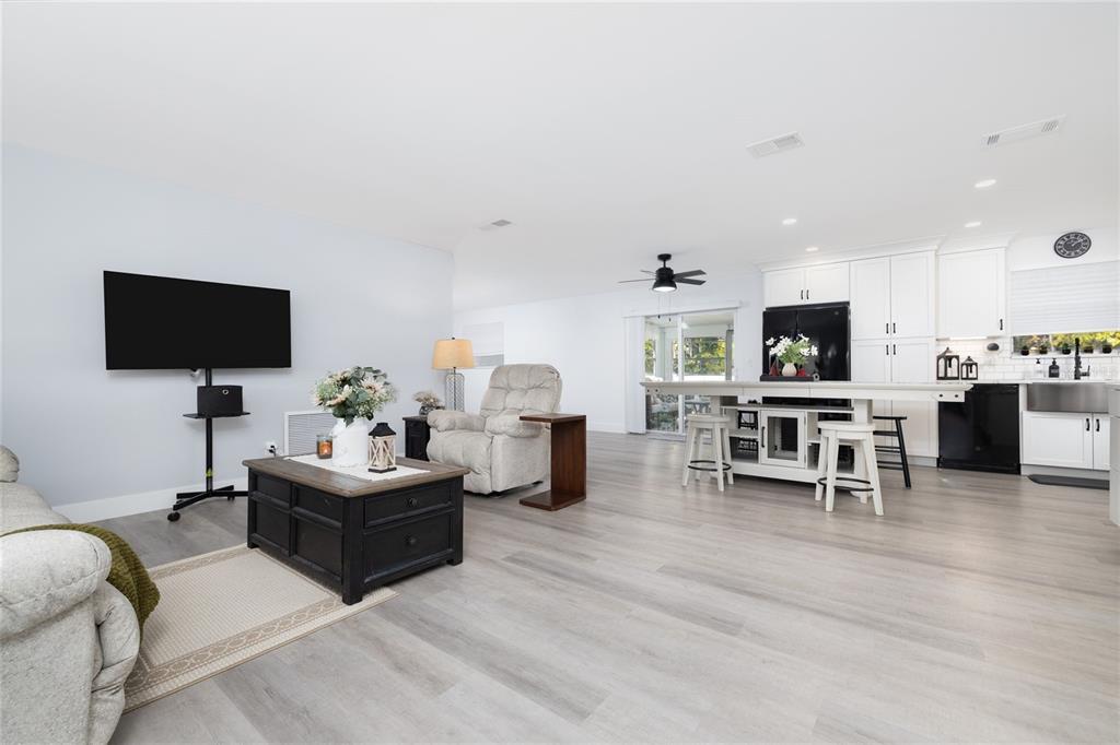 An open-concept living room and kitchen featuring light wood-look flooring and white cabinetry — 692 GASLIGHT DRIVE, SOUTH DAYTONA, FL