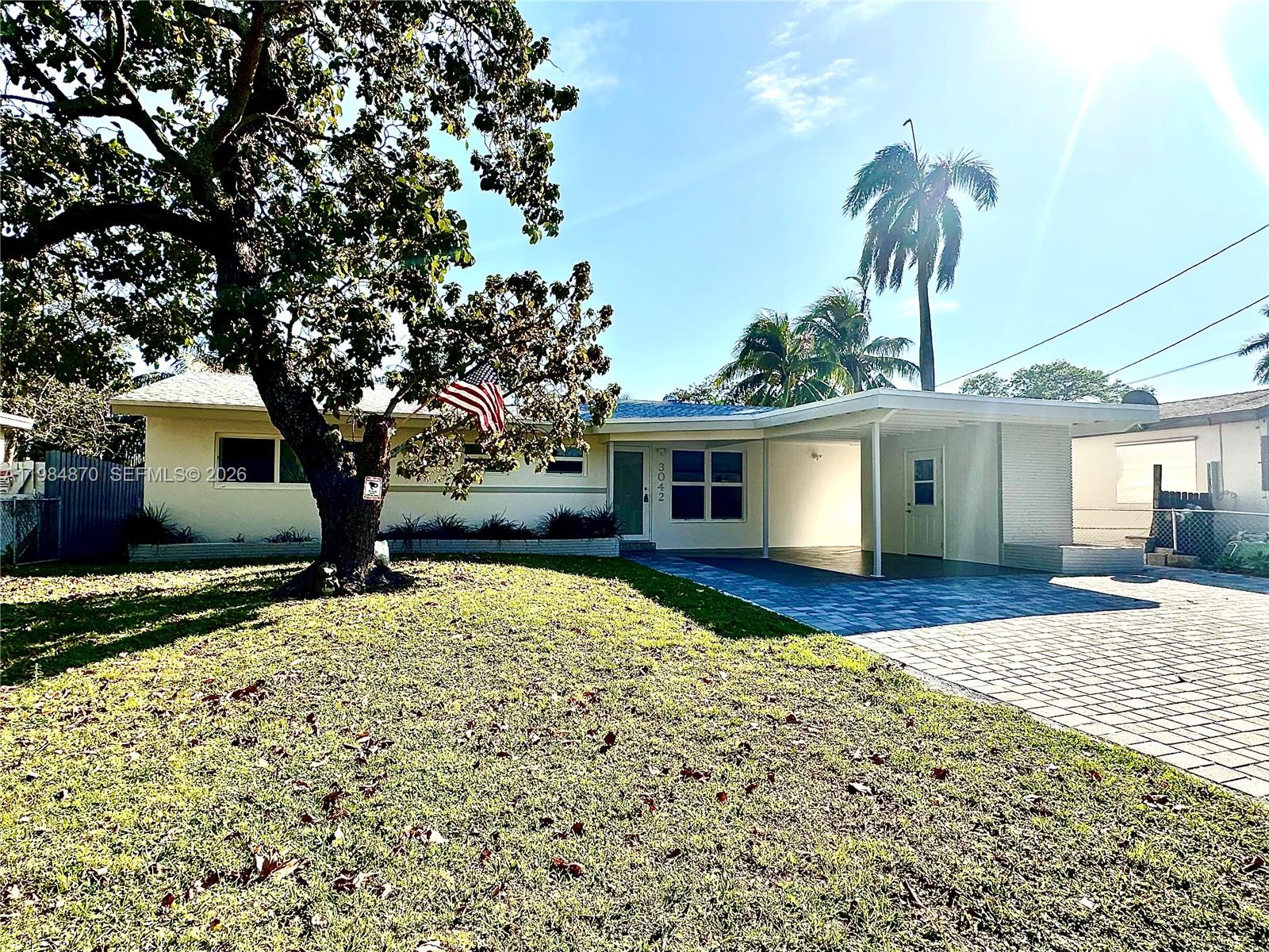 A single-story house features a paved driveway, a carport, and a large tree in front — 3042 Hayes St, Hollywood FL 33021, HOLLYWOOD, FL
