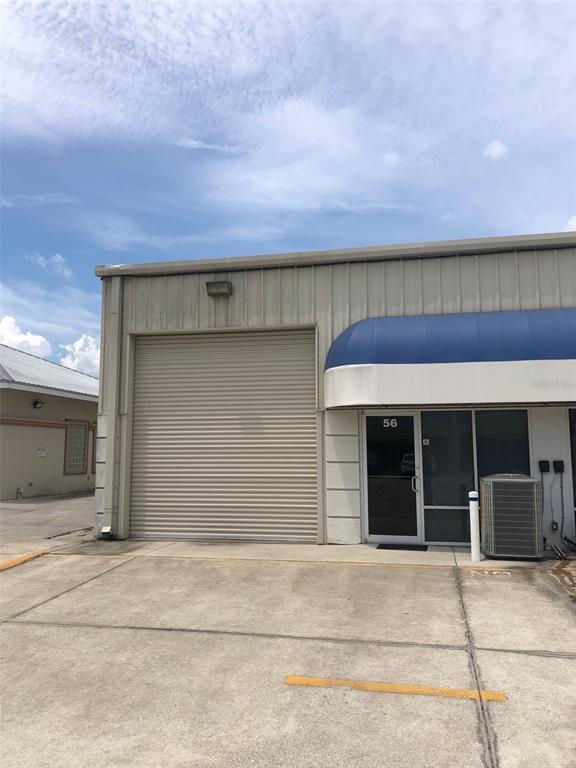 A commercial building exterior features a roll-up garage door and a glass entrance door — 2323 N STATE STREET UNIT 56, BUNNELL, FL