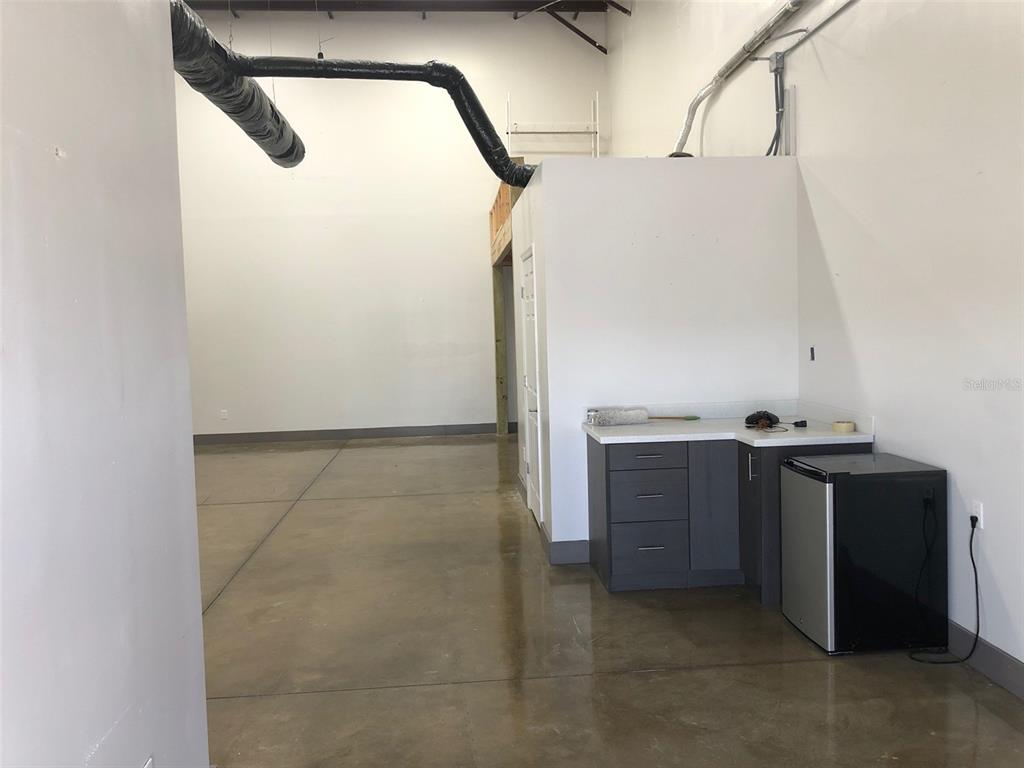 A commercial space features a polished concrete floor, exposed ductwork, and a small kitchenette area — 2323 N STATE STREET UNIT 56, BUNNELL, FL