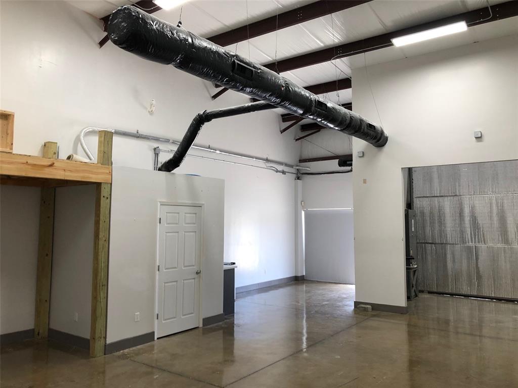 An interior view of a warehouse space featuring a concrete floor, exposed ductwork, and shelving — 2323 N STATE STREET UNIT 56, BUNNELL, FL