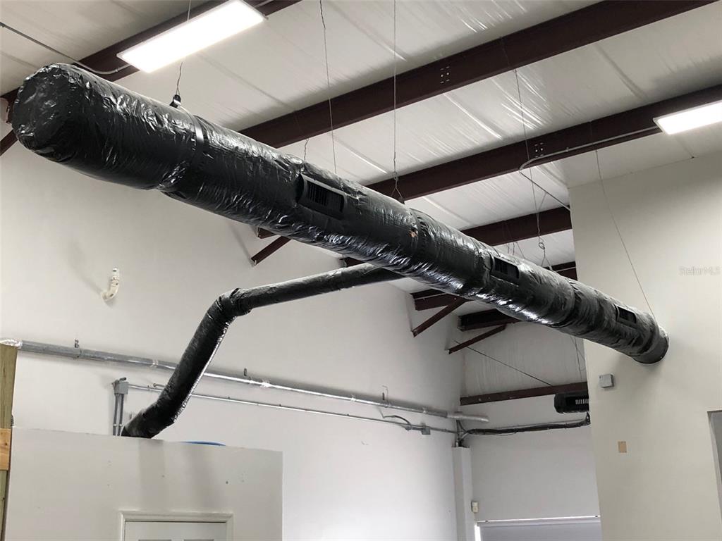 A black flexible HVAC duct system is suspended from the ceiling of an industrial space — 2323 N STATE STREET UNIT 56, BUNNELL, FL