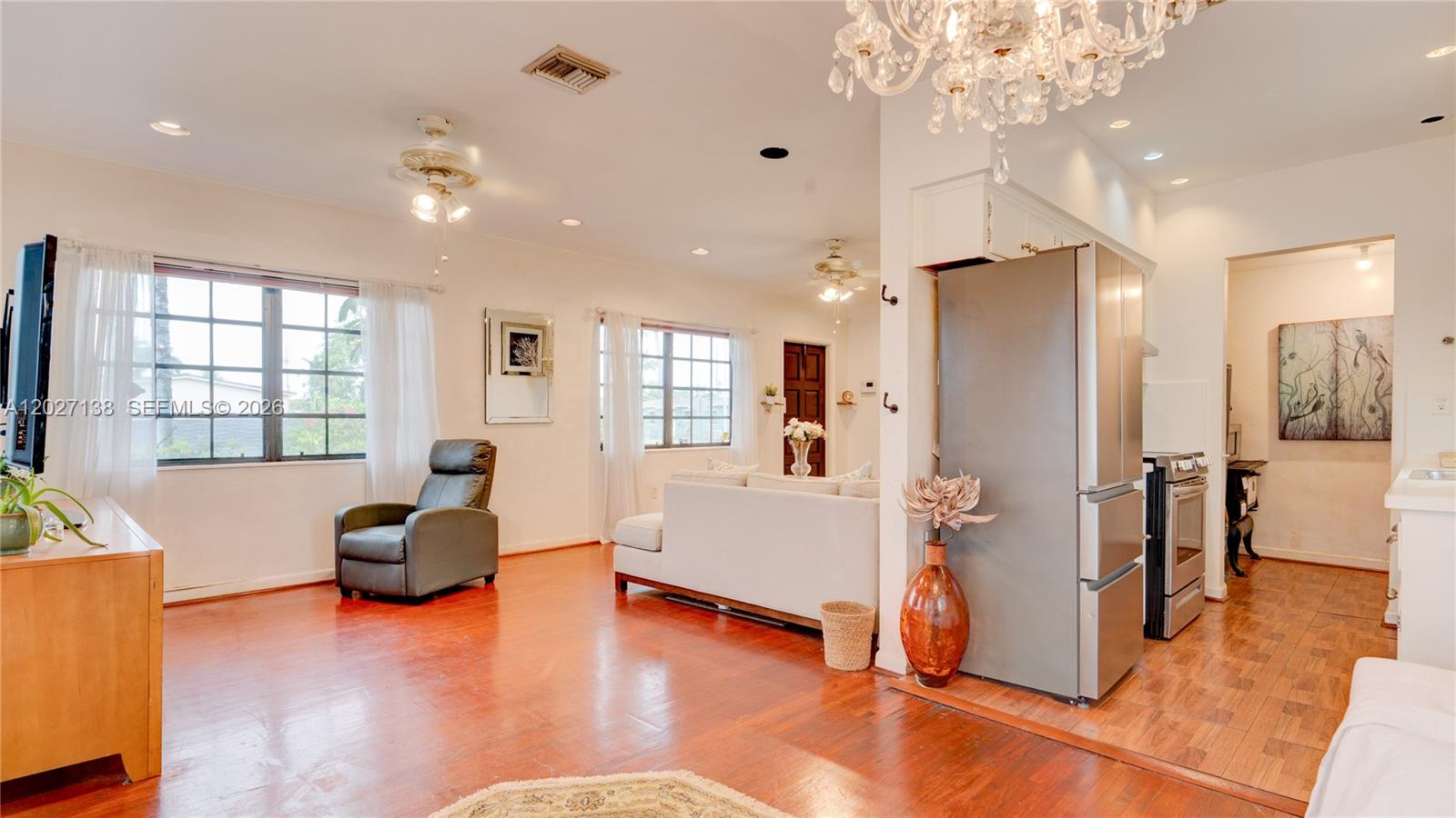 An open-concept living room and kitchen area features hardwood floors and a crystal chandelier — 10420 SW 149th St, Miami FL 33176, MIAMI, FL