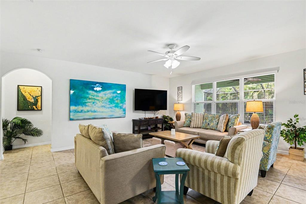 A living room features tile flooring, a ceiling fan, a large television, and neutral furniture — 15351 ANCEL CIRCLE, PORT CHARLOTTE, FL