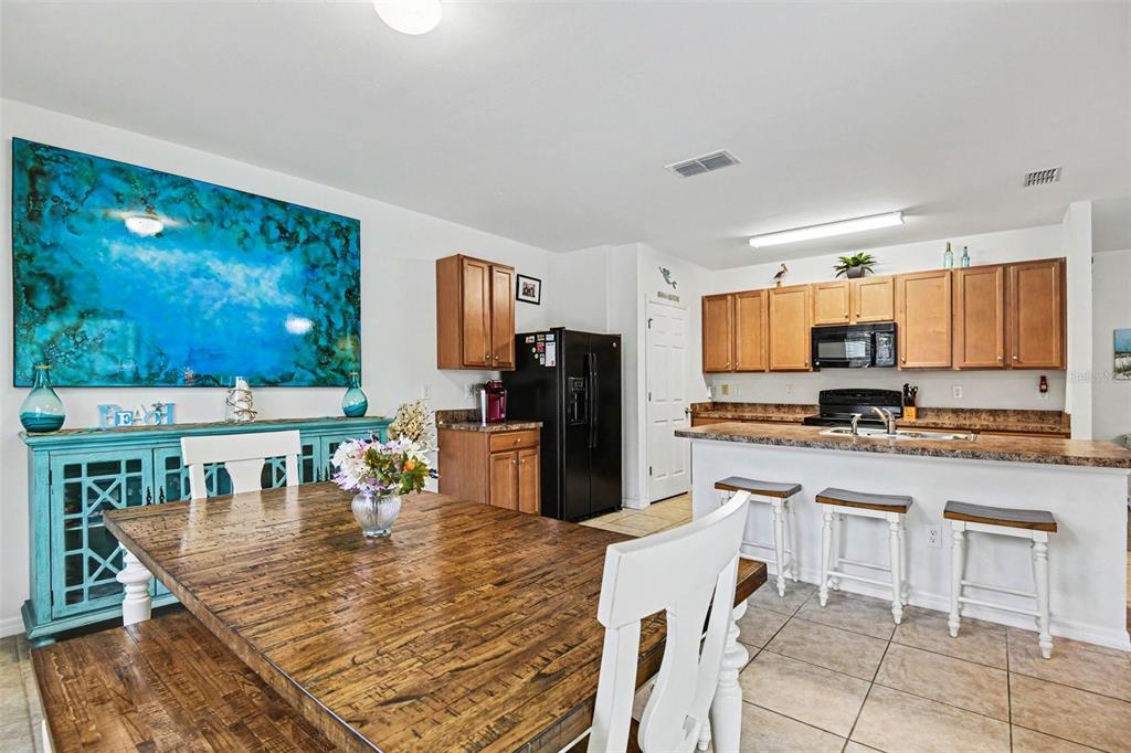 A dining area with a wooden table sits adjacent to a kitchen with wooden cabinets — 15351 ANCEL CIRCLE, PORT CHARLOTTE, FL