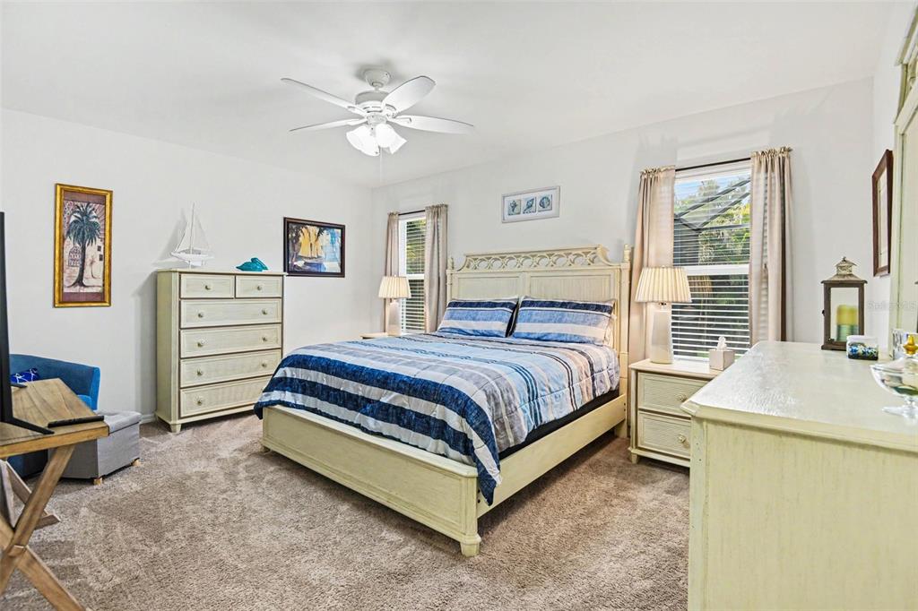 A bedroom features a bed with blue striped bedding, light-colored furniture, and a ceiling fan — 15351 ANCEL CIRCLE, PORT CHARLOTTE, FL