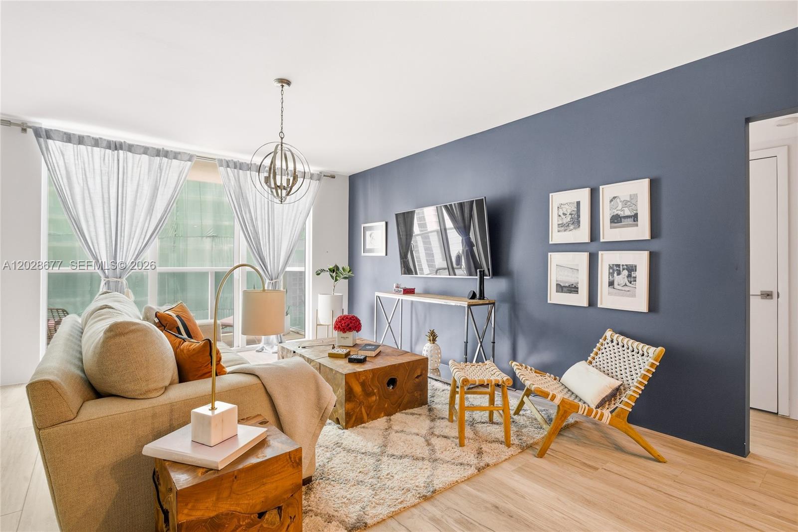 A living room features a blue accent wall, a beige sofa, and a wooden coffee table — 31 SE 5th St # 2410, Miami FL 33131, MIAMI, FL