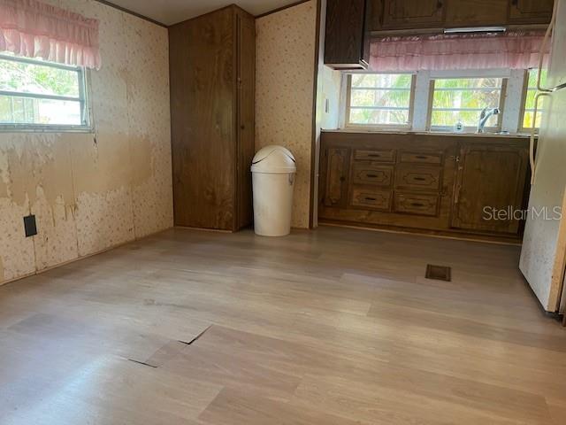 A kitchen with wood cabinets, light-colored flooring, and a white trash can near a window — 3000 CLARCONA ROAD UNIT 438, APOPKA, FL