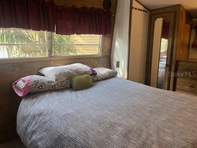 A bedroom in a mobile home features a bed with patterned pillows and wood paneling — 3000 CLARCONA ROAD UNIT 438, APOPKA, FL