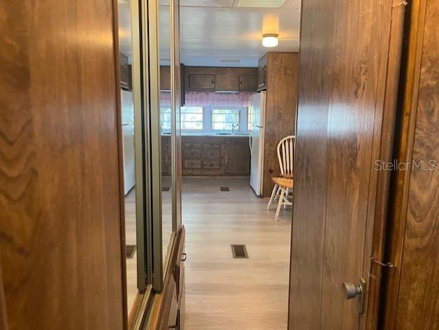 A view through a wooden doorway into a kitchen with light wood-look flooring — 3000 CLARCONA ROAD UNIT 438, APOPKA, FL