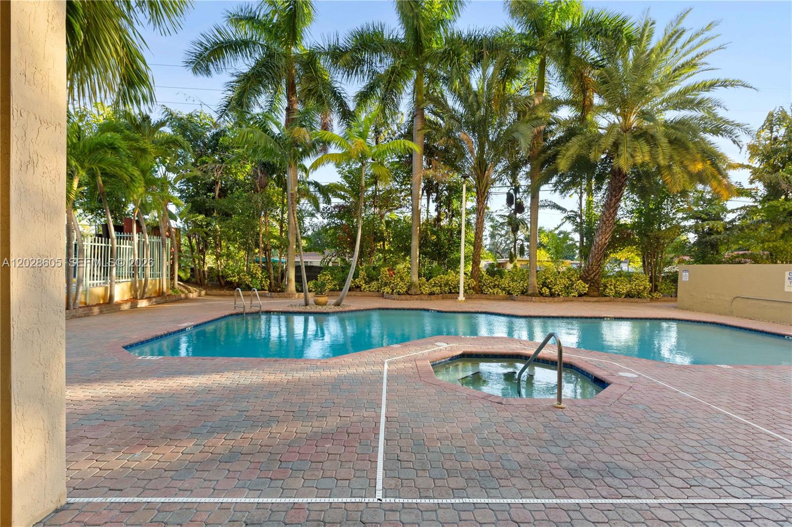 A swimming pool and a hot tub are surrounded by a brick patio and palms — 3500 Coral Way # 614, Miami FL 33145, MIAMI, FL