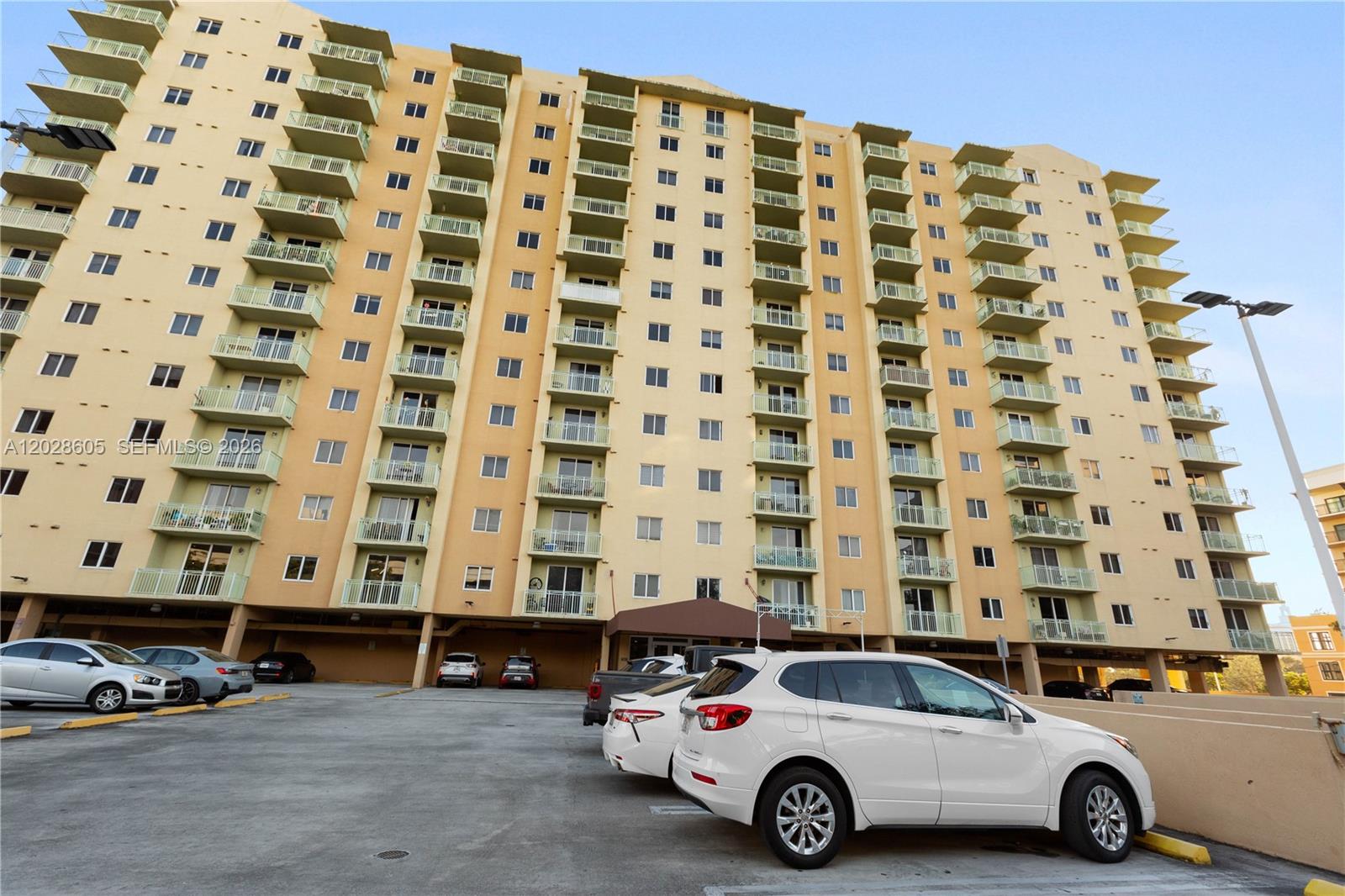 A multi-story apartment building features numerous balconies and a ground-level parking lot — 3500 Coral Way # 614, Miami FL 33145, MIAMI, FL