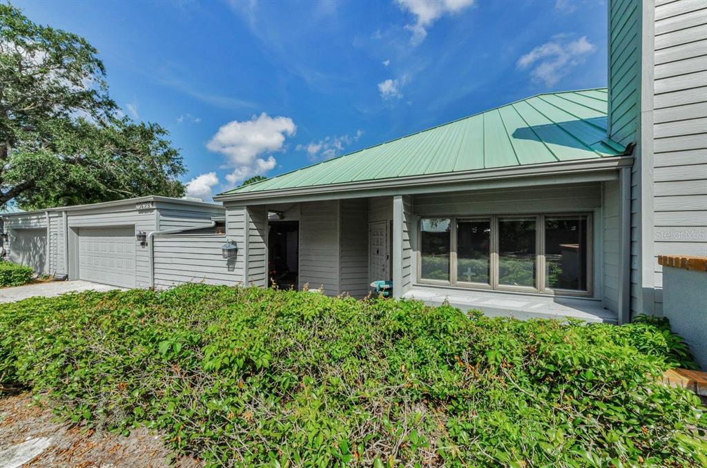 A brick walkway leads to a light gray house entrance with a paneled front door — 10479 LONGWOOD DRIVE, SEMINOLE, FL