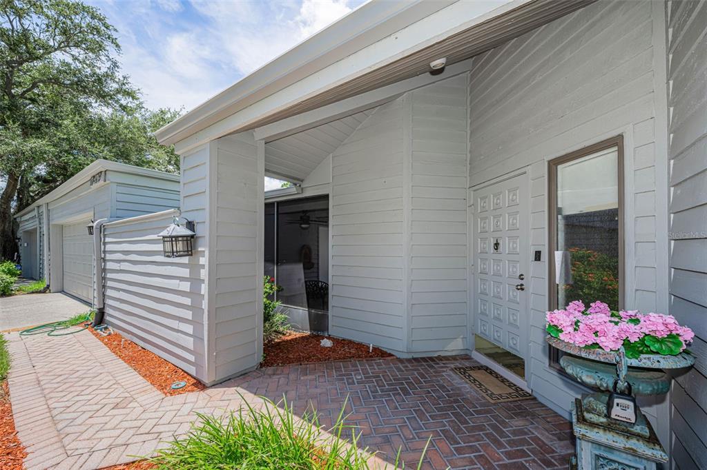 A gray house with a green metal roof and a brick walkway leading to the entrance — 10479 LONGWOOD DRIVE, SEMINOLE, FL