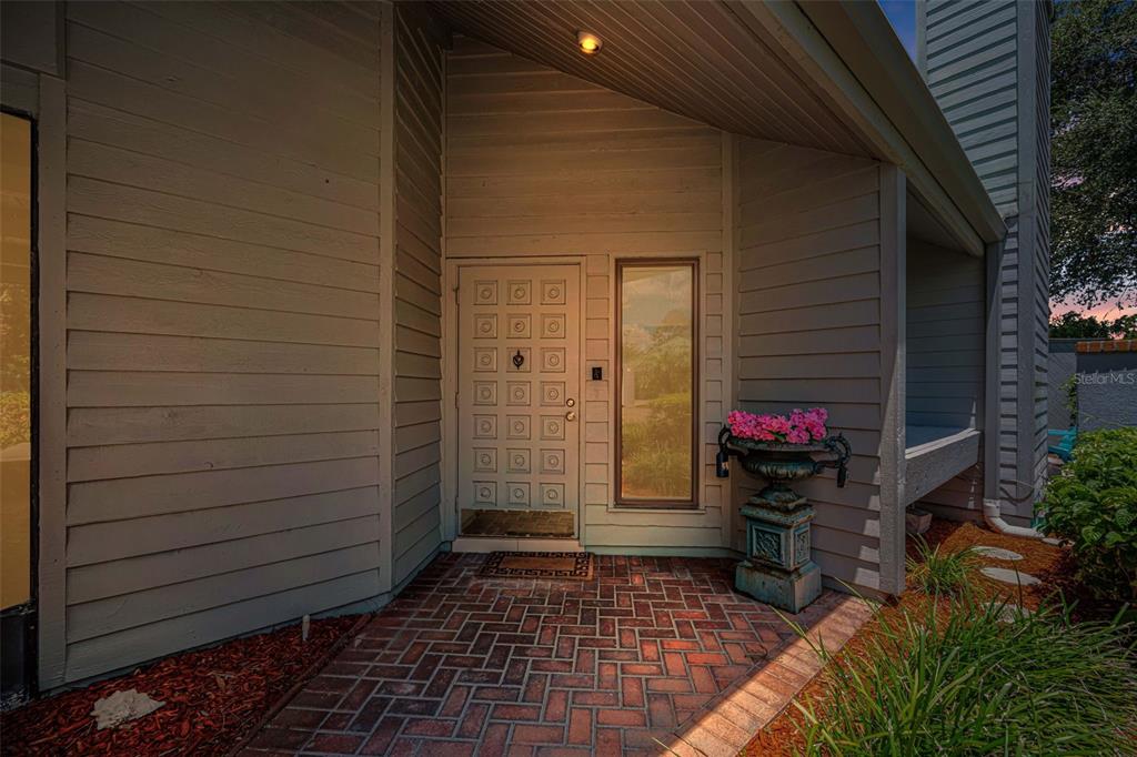 A palm tree stands in a landscaped front yard before a house with a metal roof — 10479 LONGWOOD DRIVE, SEMINOLE, FL