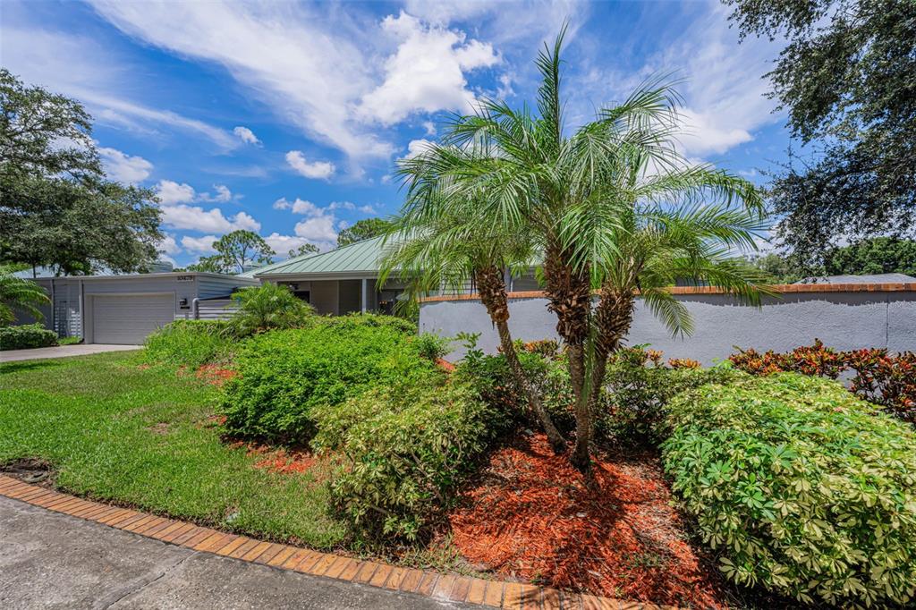 A front entryway features a gray paneled door, a side window, and a decorative pedestal planter — 10479 LONGWOOD DRIVE, SEMINOLE, FL