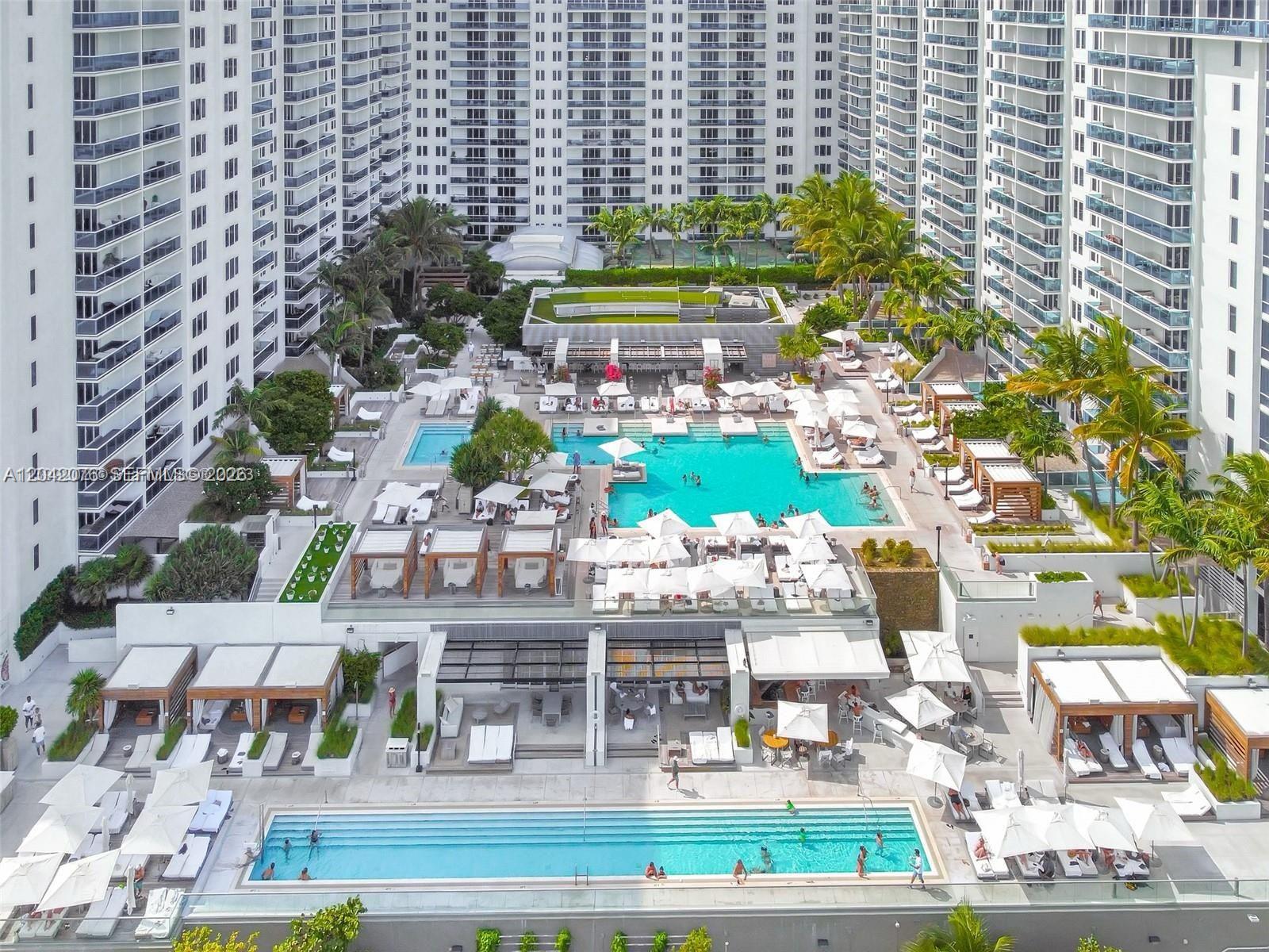 An aerial view shows a large resort pool deck with multiple swimming pools and cabanas — 2301 Collins Ave # 420, Miami Beach FL 33139, MIAMI BEACH, FL