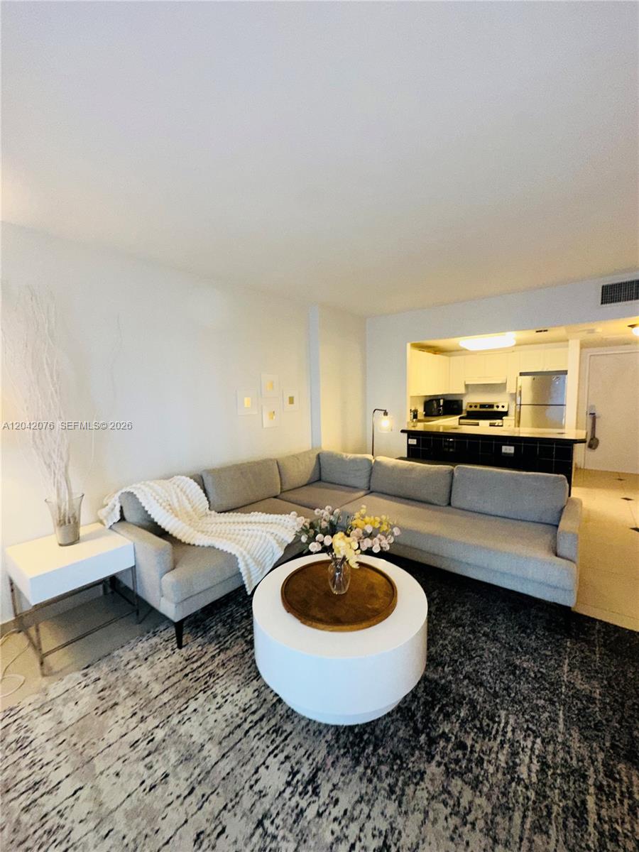 A living room features a gray sectional sofa, a white coffee table, and an open kitchen — 2301 Collins Ave # 420, Miami Beach FL 33139, MIAMI BEACH, FL