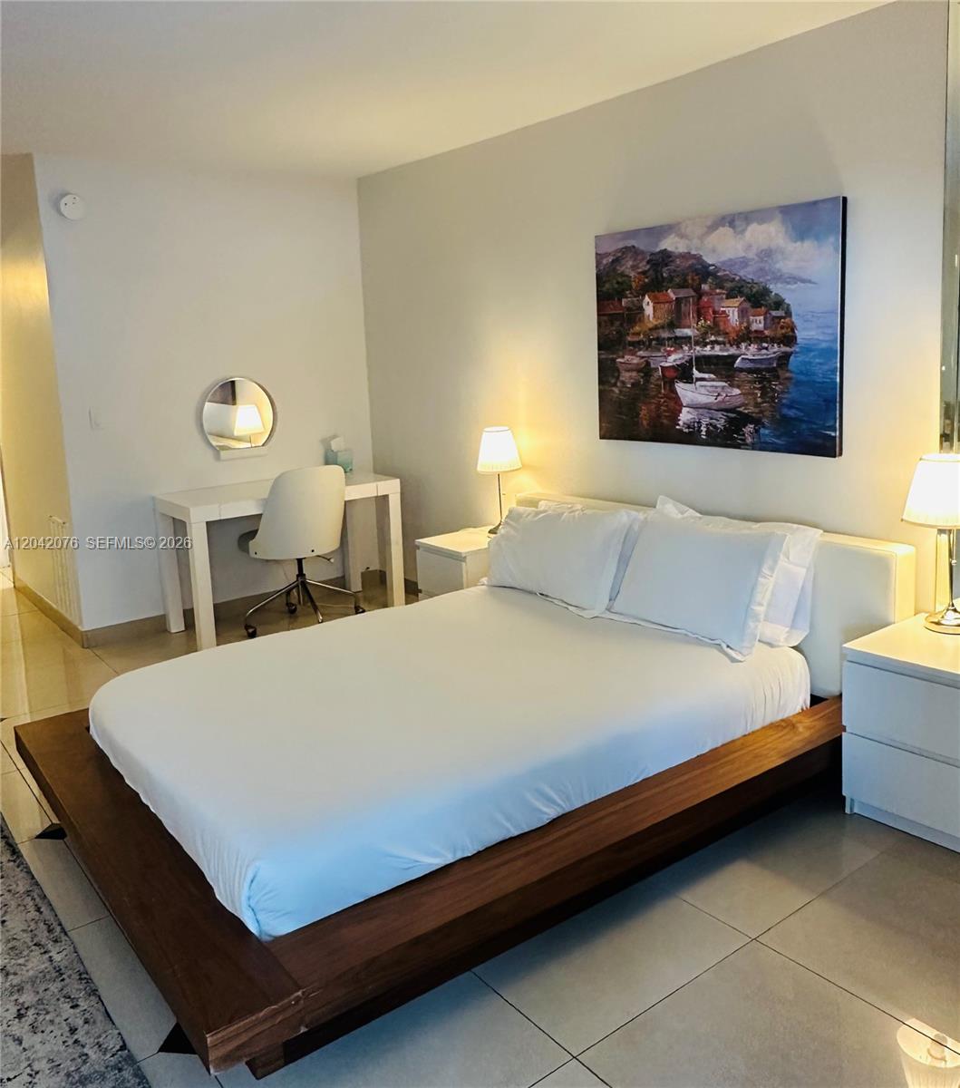 A bedroom features a platform bed, white nightstands, a desk, and a coastal landscape painting — 2301 Collins Ave # 420, Miami Beach FL 33139, MIAMI BEACH, FL