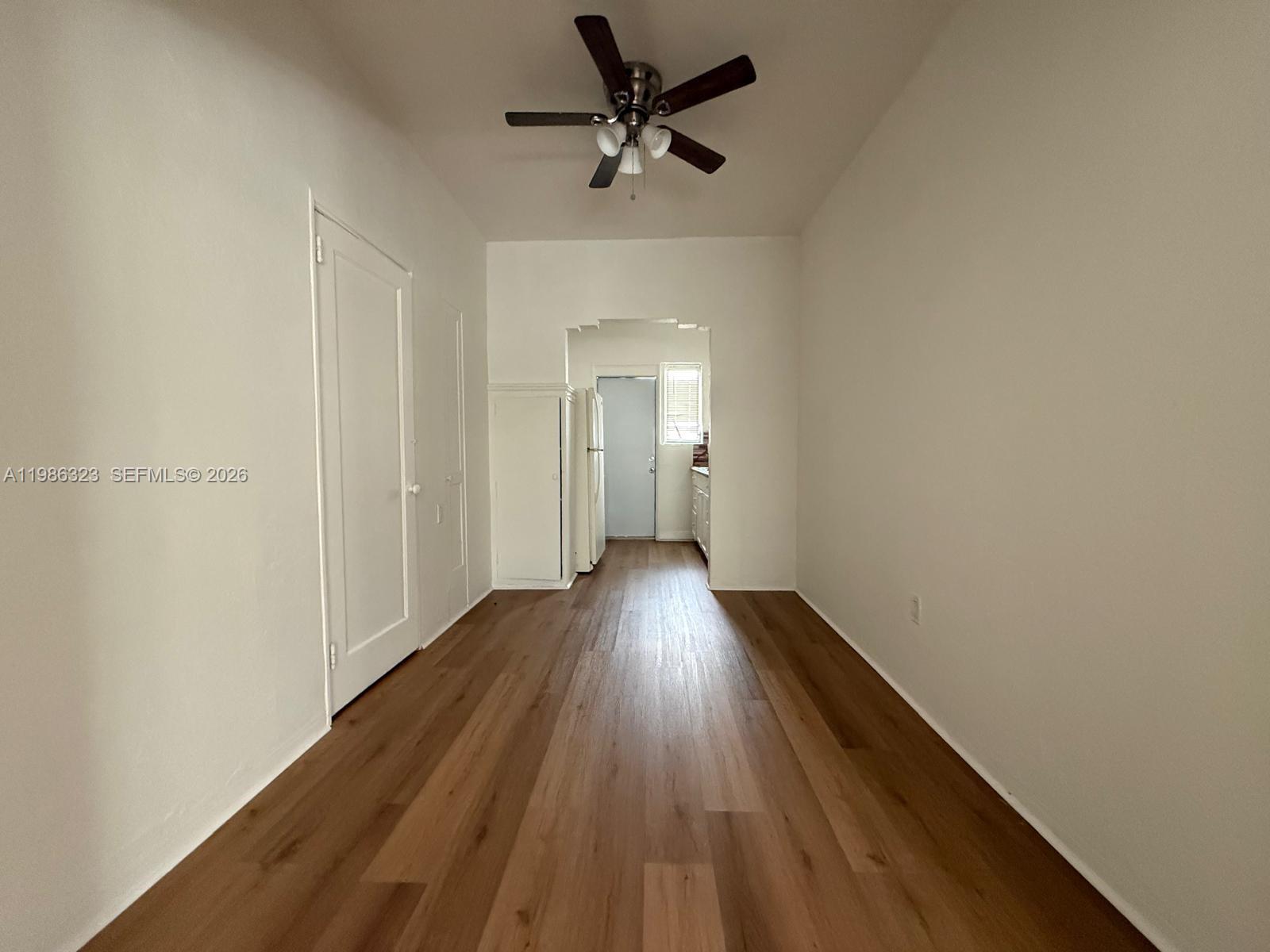 A narrow room features light wood-look flooring, white walls, and a ceiling fan — 6830 Harding Ave # 1, Miami Beach FL 33141, MIAMI BEACH, FL