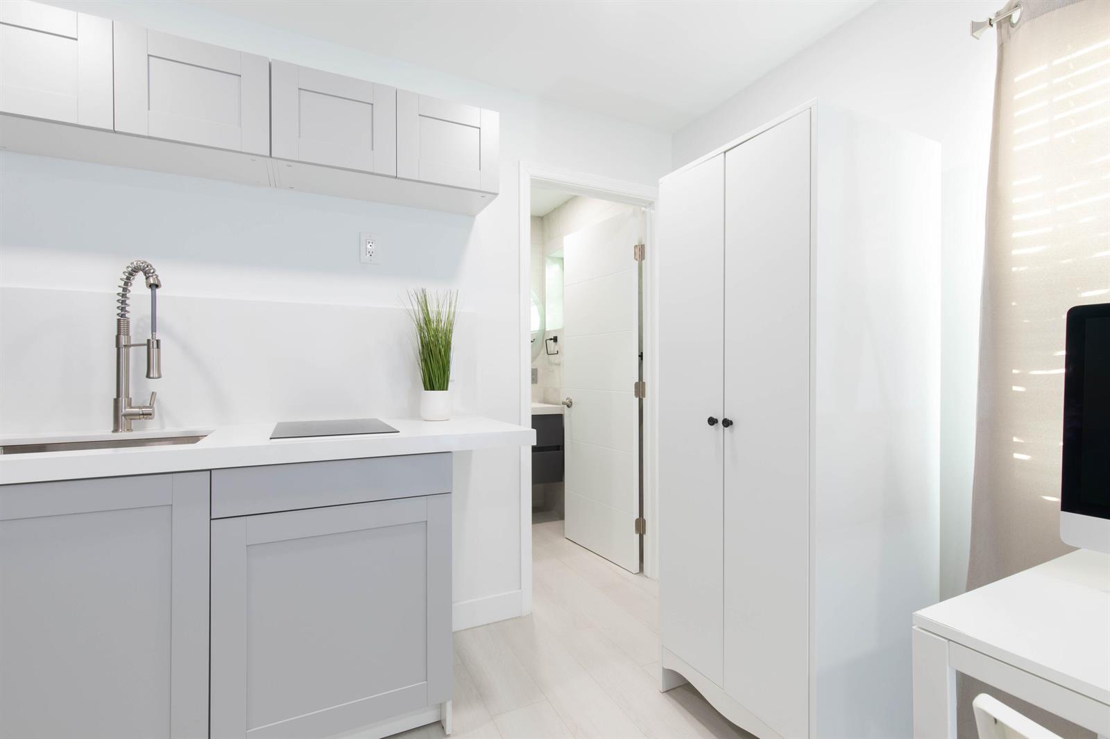 A small kitchen area with gray cabinets, a white countertop, and a tall white wardrobe — 1826 Jefferson Street, Hollywood FL 33020, HOLLYWOOD, FL
