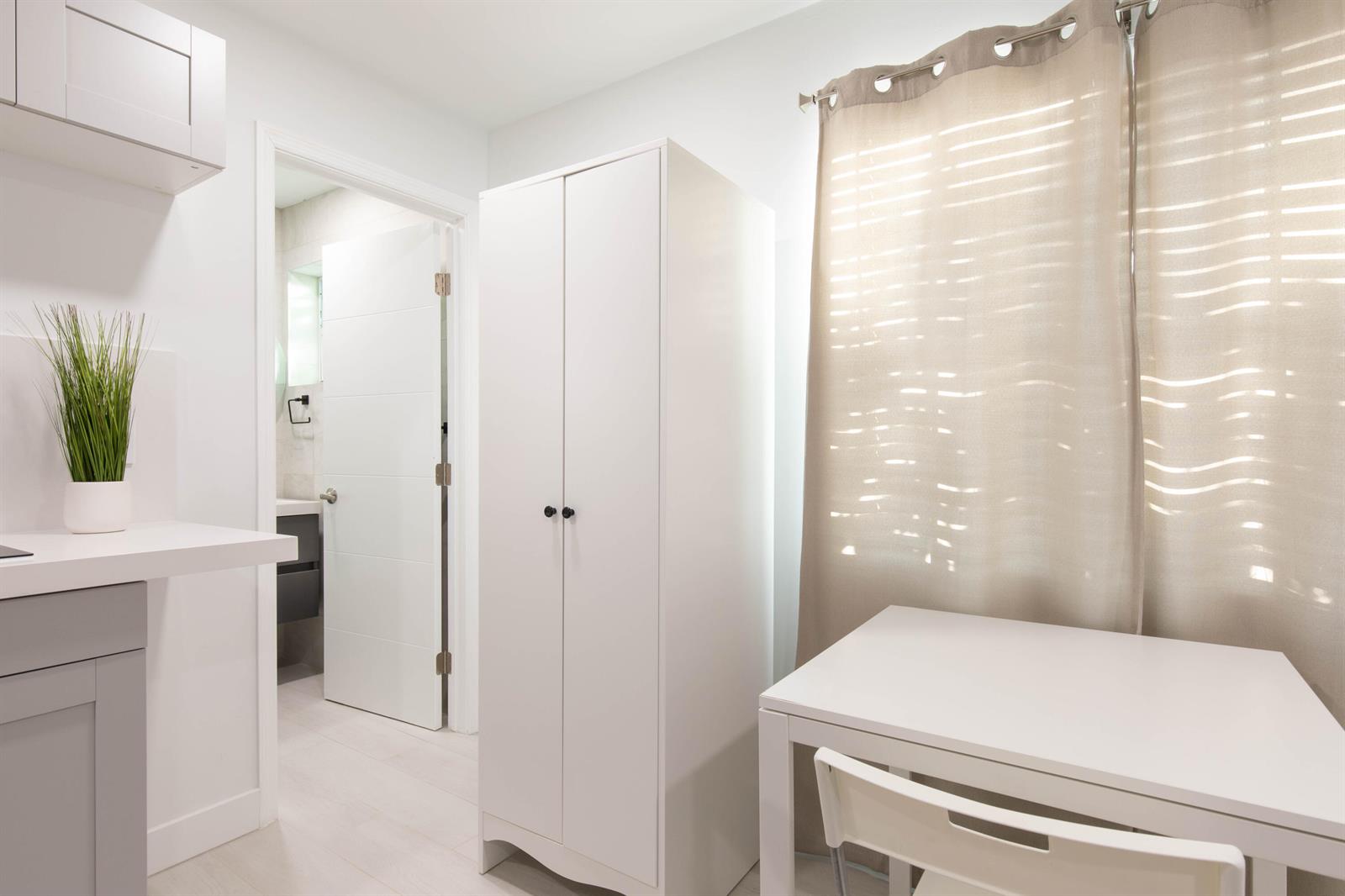 A white room features a wardrobe, a small table with a chair, and a doorway — 1826 Jefferson Street, Hollywood FL 33020, HOLLYWOOD, FL