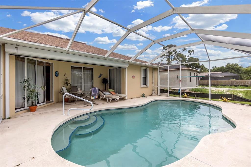 A swimming pool with steps sits inside a screened-in patio next to a house — 2260 ZUYDER TERRACE, NORTH PORT, FL