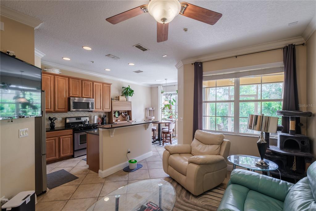 An open-concept kitchen and living area features wood cabinets, tile flooring, and large windows — 873 ASSEMBLY COURT, REUNION, FL