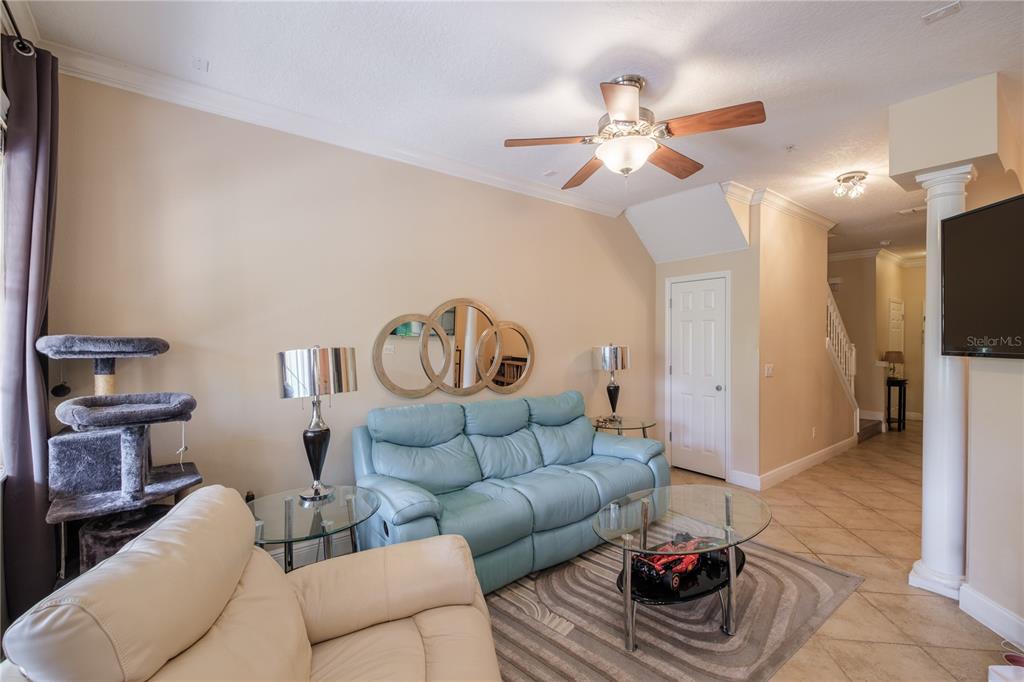 A living room features a blue sofa, a cream armchair, and a glass coffee table — 873 ASSEMBLY COURT, REUNION, FL