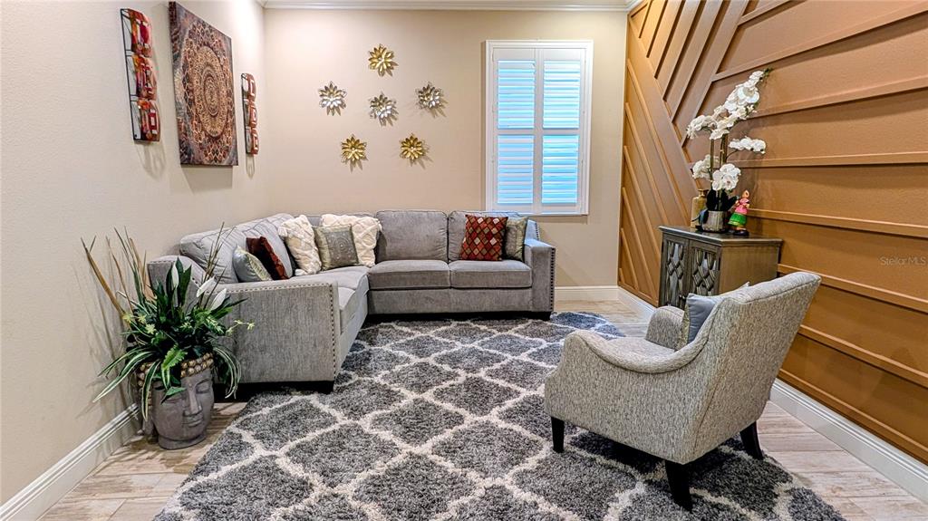 A living room features a gray sectional sofa, an accent chair, and a wood-paneled wall — 2468 WHITTLER BRANCH, ODESSA, FL
