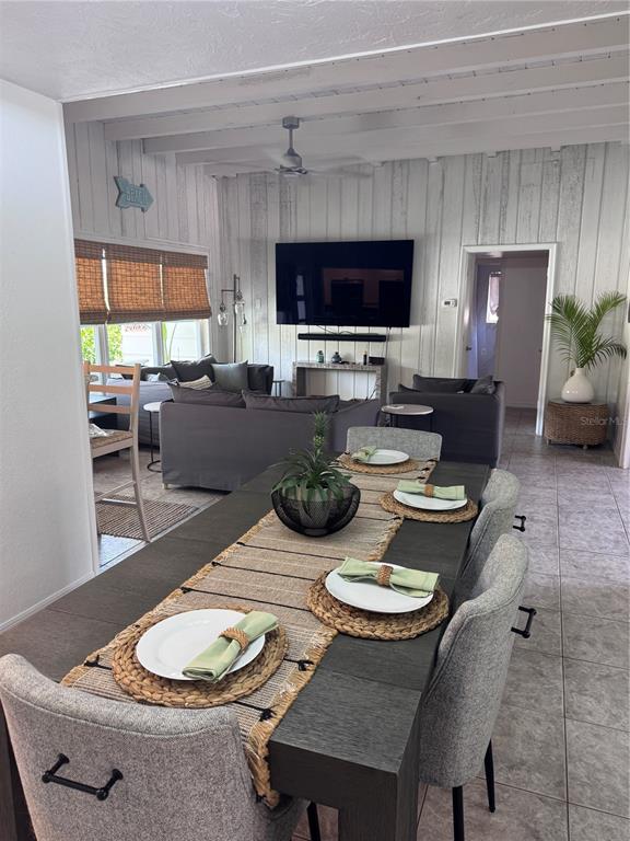 A dining area with a dark table and grey chairs opens into a living room — 6304 BEECHWOOD AVENUE, SARASOTA, FL
