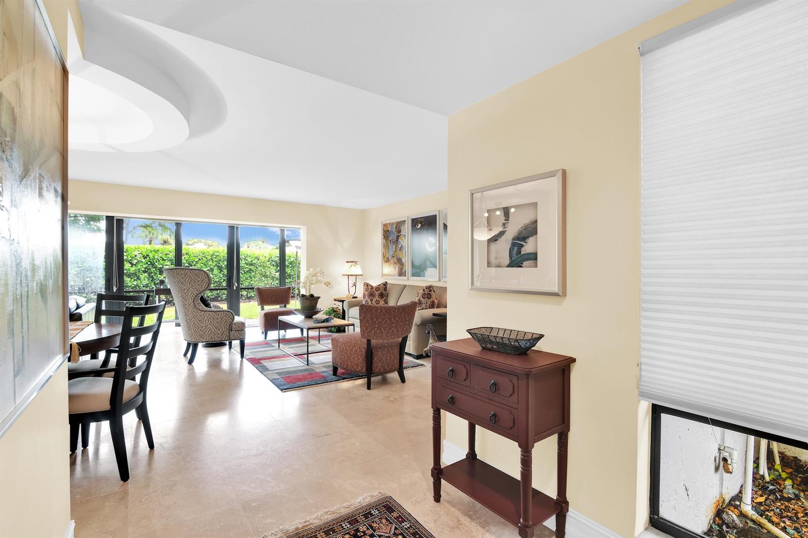 A living and dining area with tile floors, large windows, and a dark wood console table — 6760 Willow Wood Drive # 1201, Boca Raton FL 33434, BOCA RATON, FL