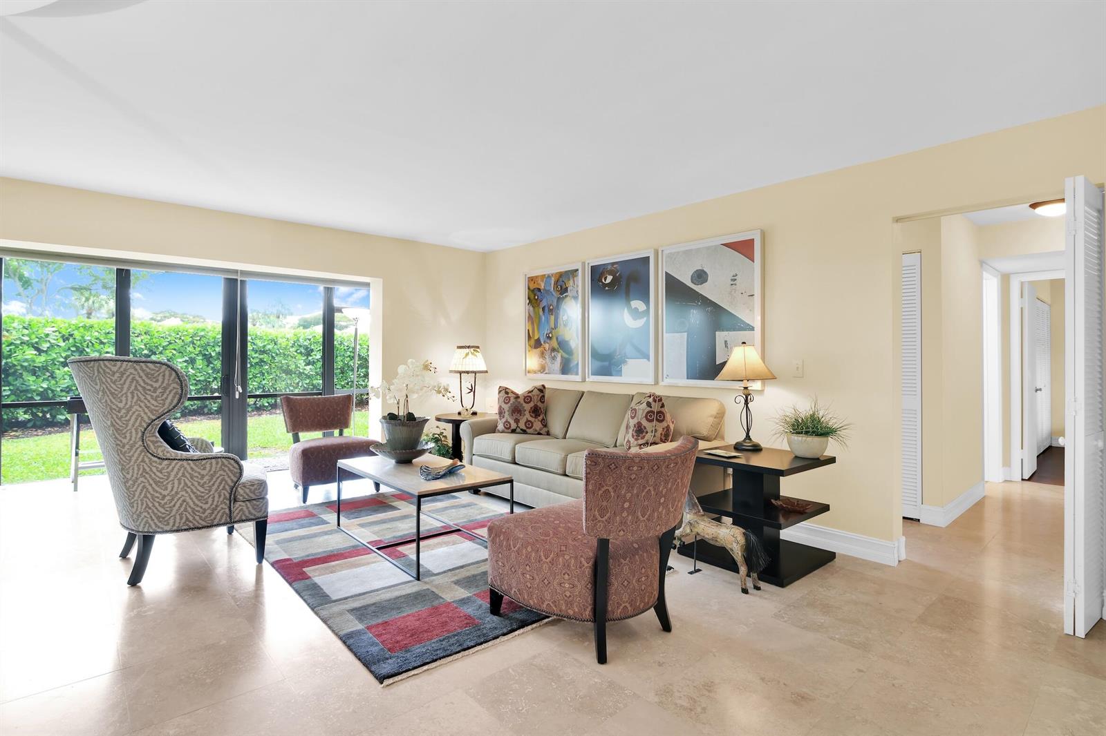 A living room features a patterned rug, a beige sofa, accent chairs, and large windows — 6760 Willow Wood Drive # 1201, Boca Raton FL 33434, BOCA RATON, FL