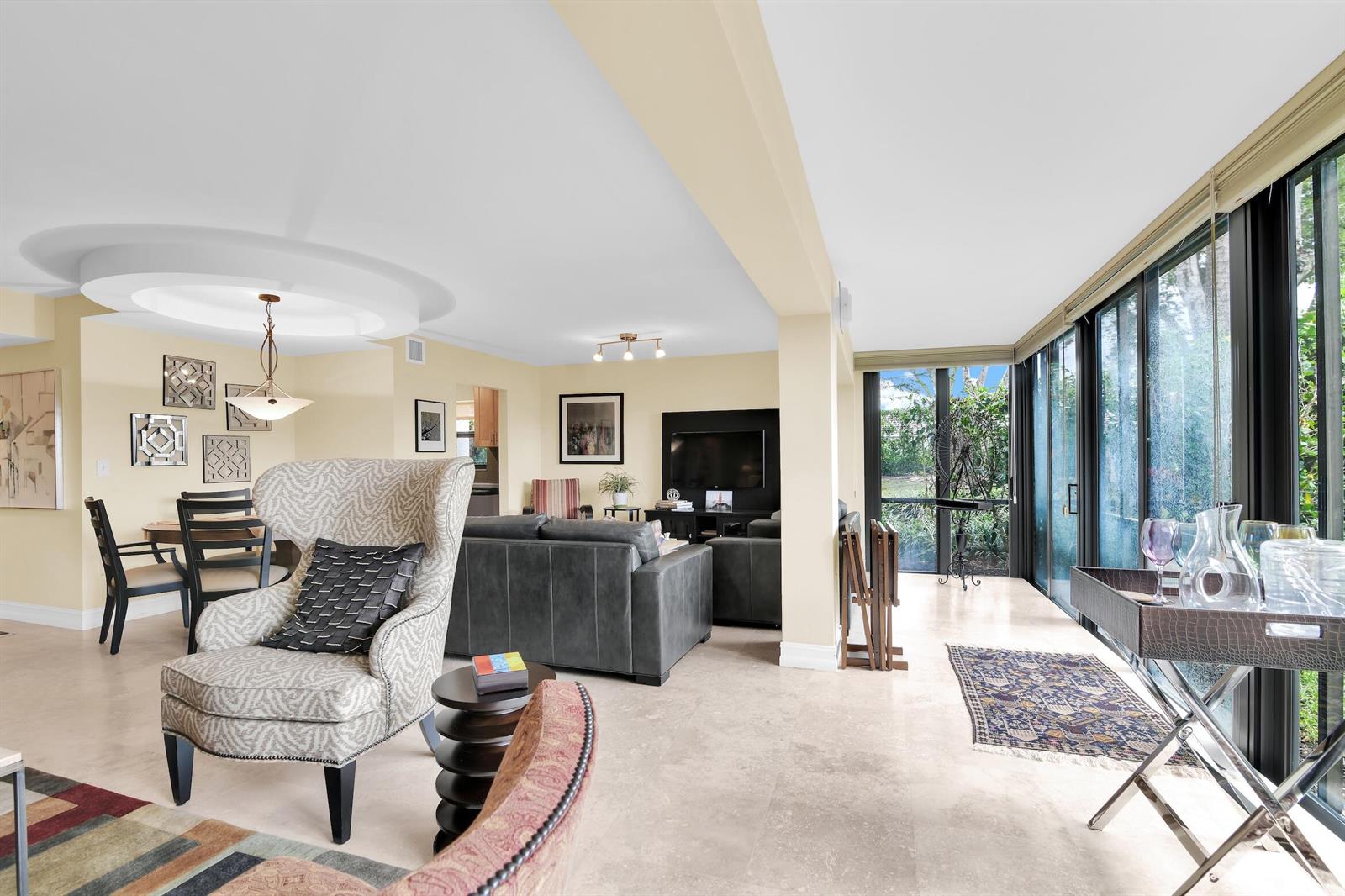 A living and dining area with light tile floors, neutral walls, and large glass windows — 6760 Willow Wood Drive # 1201, Boca Raton FL 33434, BOCA RATON, FL