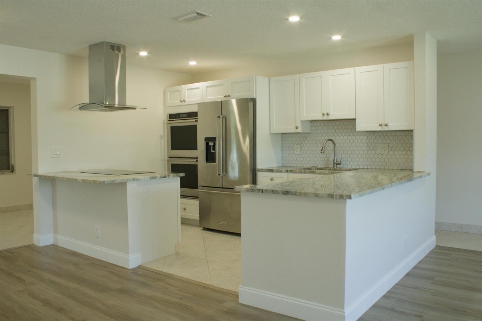 A kitchen with white cabinets, stainless steel appliances, granite countertops, and a hexagonal tile backsplash — 14243 EL CLAVEL Way, Delray Beach FL 33484, DELRAY BEACH, FL