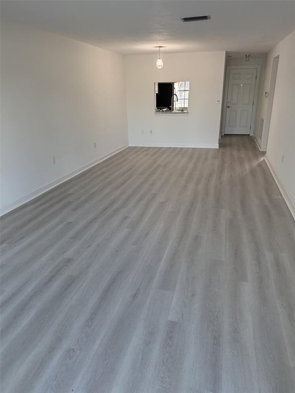 An empty room with light wood-look flooring, white walls, and a kitchen pass-through window — 4413 SUNSTATE DRIVE UNIT 0, NEW PORT RICHEY, FL