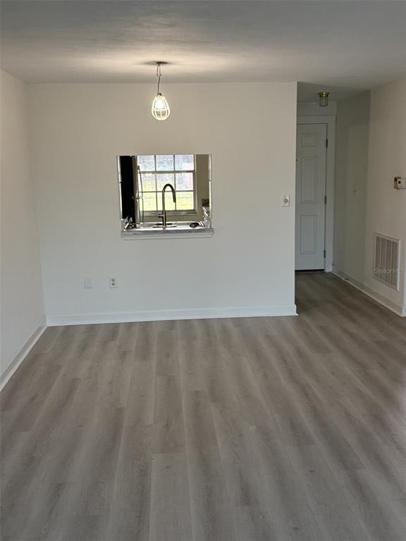 A room with light-colored wood-look flooring, white walls, and a pass-through window to the kitchen — 4413 SUNSTATE DRIVE UNIT 0, NEW PORT RICHEY, FL