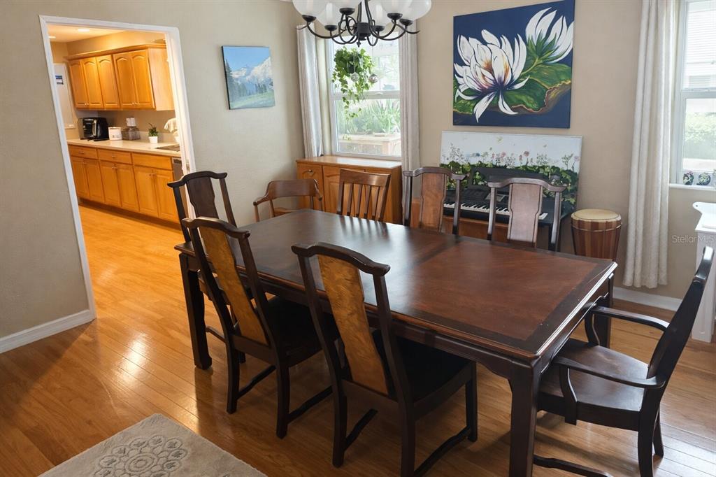 A dining room features a dark wood table, six chairs, and a view into the kitchen — 321 ROSLYN AVENUE, NEW SMYRNA BEACH, FL