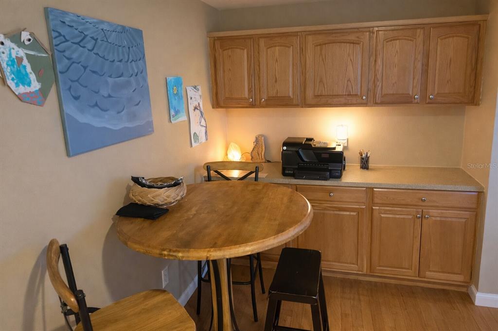 A dining area features a round wooden table, chairs, and light wood cabinetry with countertops — 321 ROSLYN AVENUE, NEW SMYRNA BEACH, FL