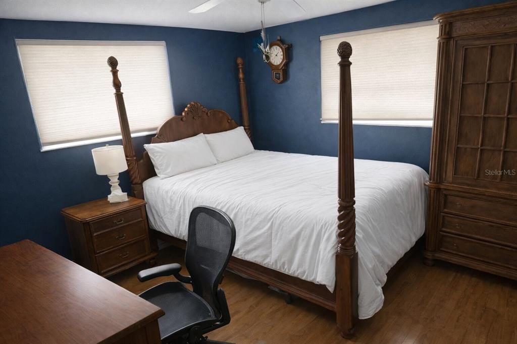 A bedroom with dark blue walls, a four-poster wooden bed, and a wooden armoire — 321 ROSLYN AVENUE, NEW SMYRNA BEACH, FL