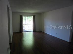 A living room with dark wood flooring and a sliding glass door leading to a balcony — 801 RUSSELL LANE UNIT 254, BRANDON, FL