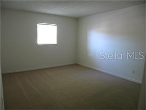 An empty bedroom features beige carpet, plain white walls, and a single window — 801 RUSSELL LANE UNIT 254, BRANDON, FL