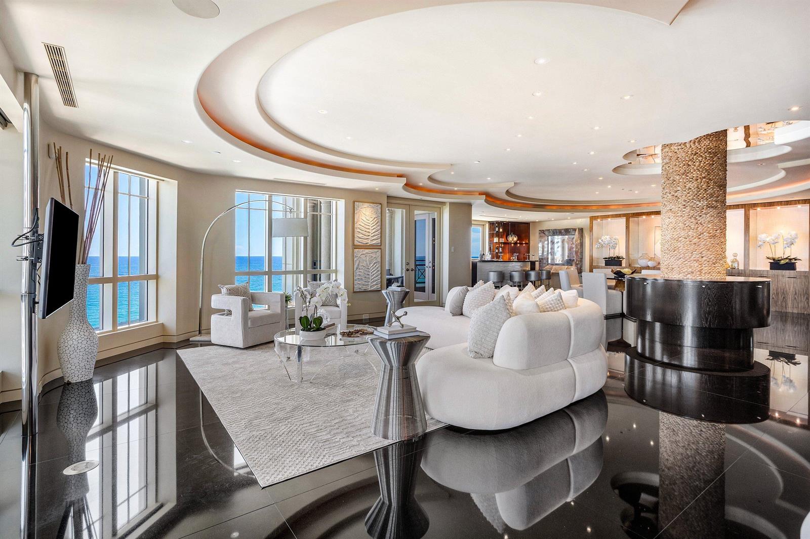 A modern living room features a curved white sofa, black tile floors, and ocean views — 400 S Ocean Boulevard, Boca Raton FL 33432, BOCA RATON, FL
