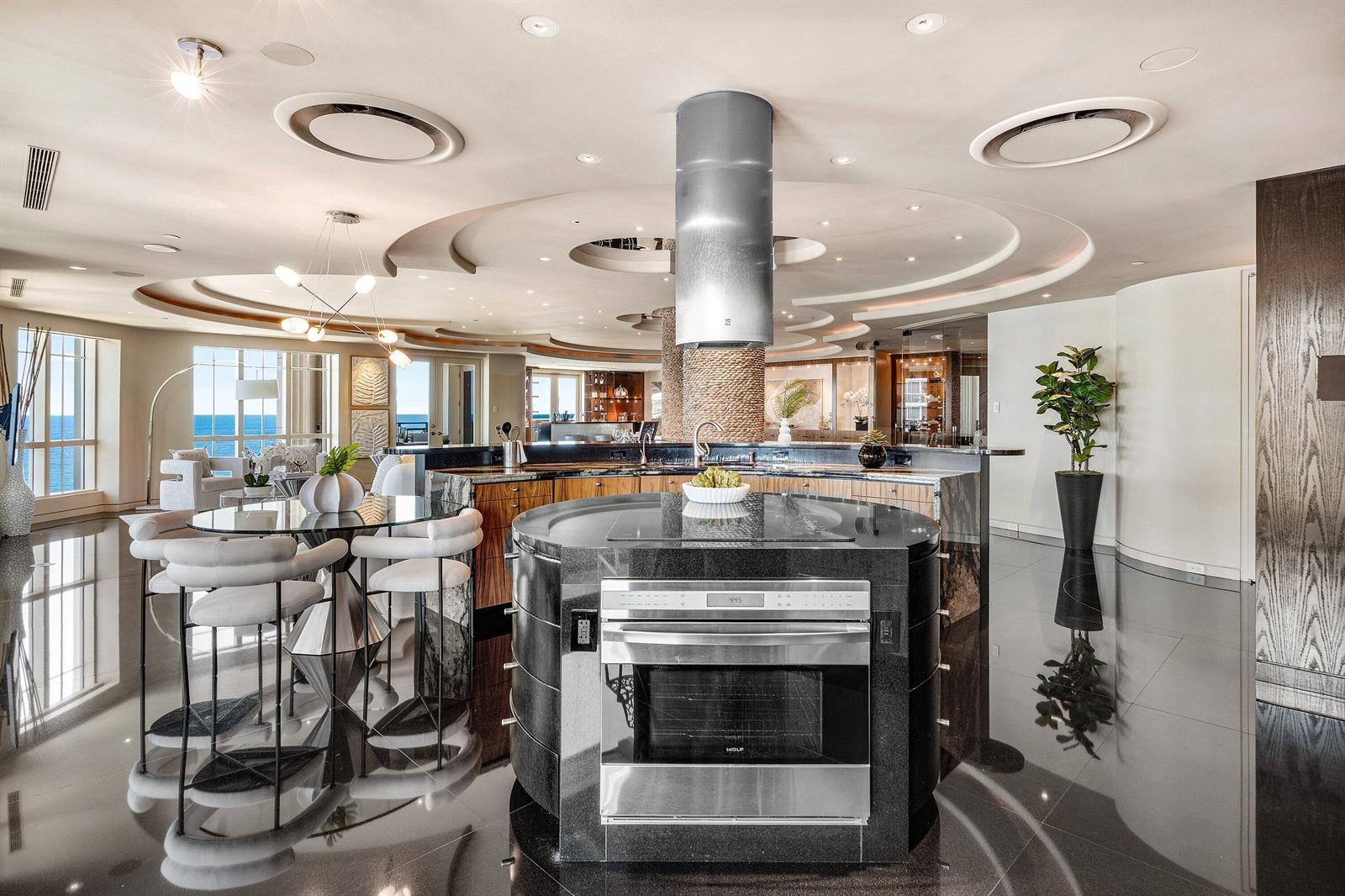 A modern kitchen features a circular black granite island with a built-in oven and hood — 400 S Ocean Boulevard, Boca Raton FL 33432, BOCA RATON, FL